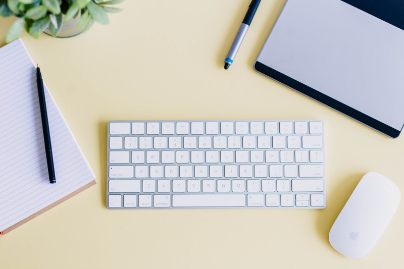 A keyboard, mouse, pad of paper and pen